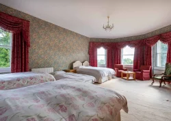 A double bed, 3 single beds and a camp bed in the Bluebell bedroom. There is also multiple armchairs in the room.