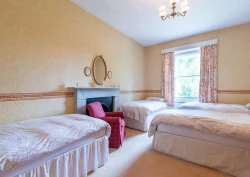 Four single beds and a red armchair in the Heather bedroom
