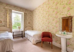 Two single beds, a red armchair and a sink in the Lilac bedroom