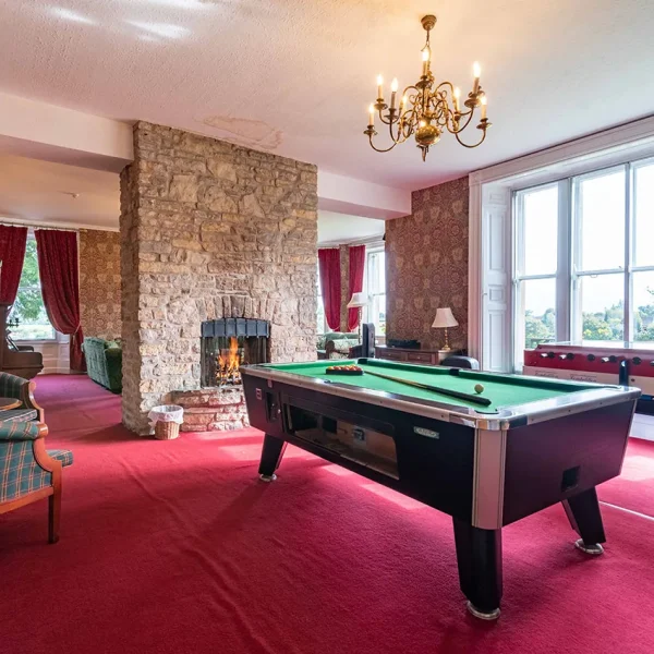 The lounge games area showing table football and a pool table with a fireplace in the background.
