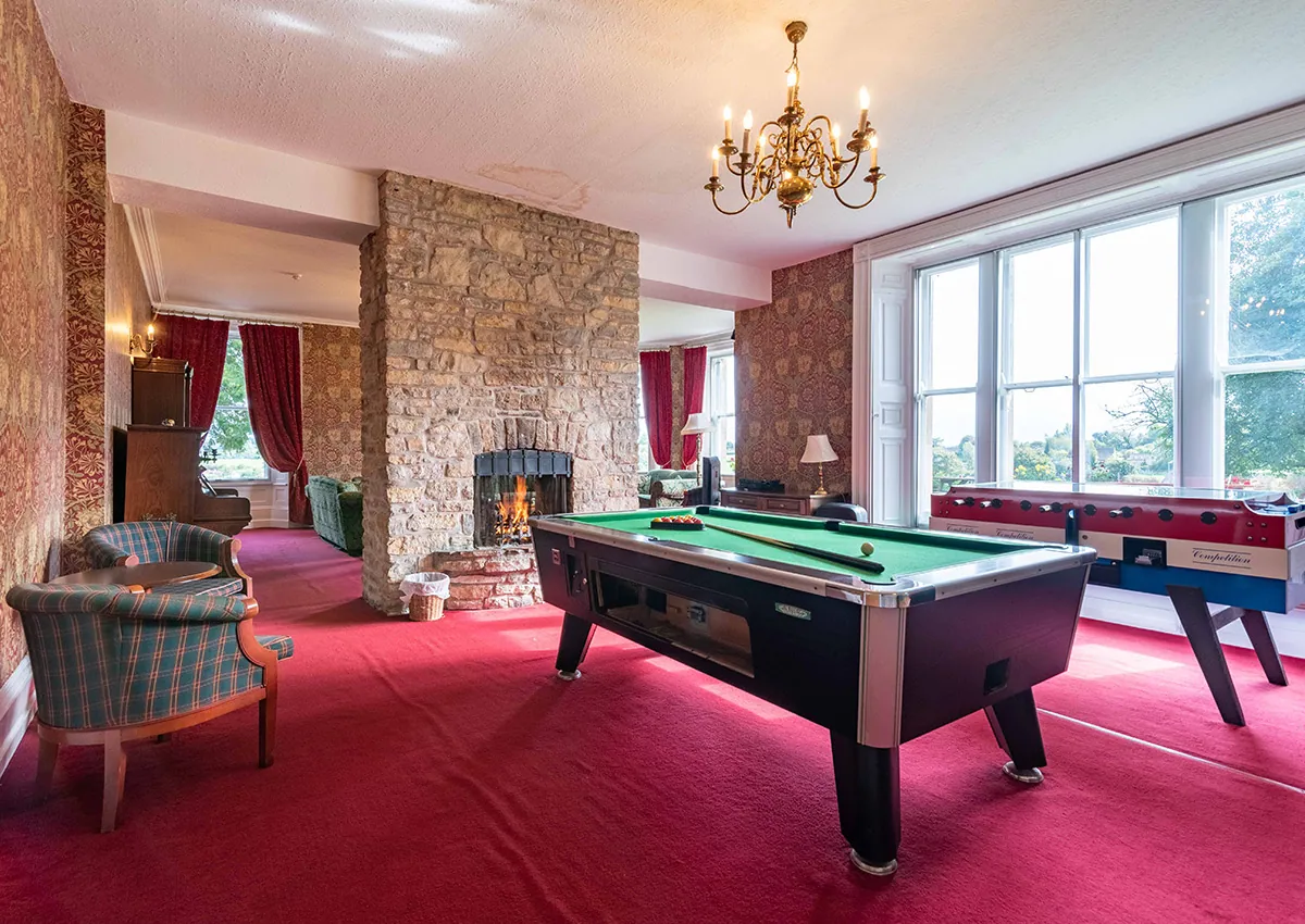 The lounge games area showing table football and a pool table with a fireplace in the background.
