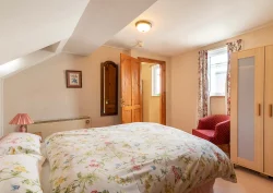 A double bed and a red armchair in the The Peony suite first bedroom