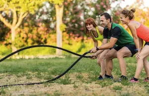 A man using a battle-rope while a lady looks on